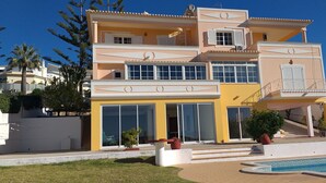 A multi-story building with balconies, large windows, and a swimming pool. - Villa with private pool, terrace and sea views (Albufeira)