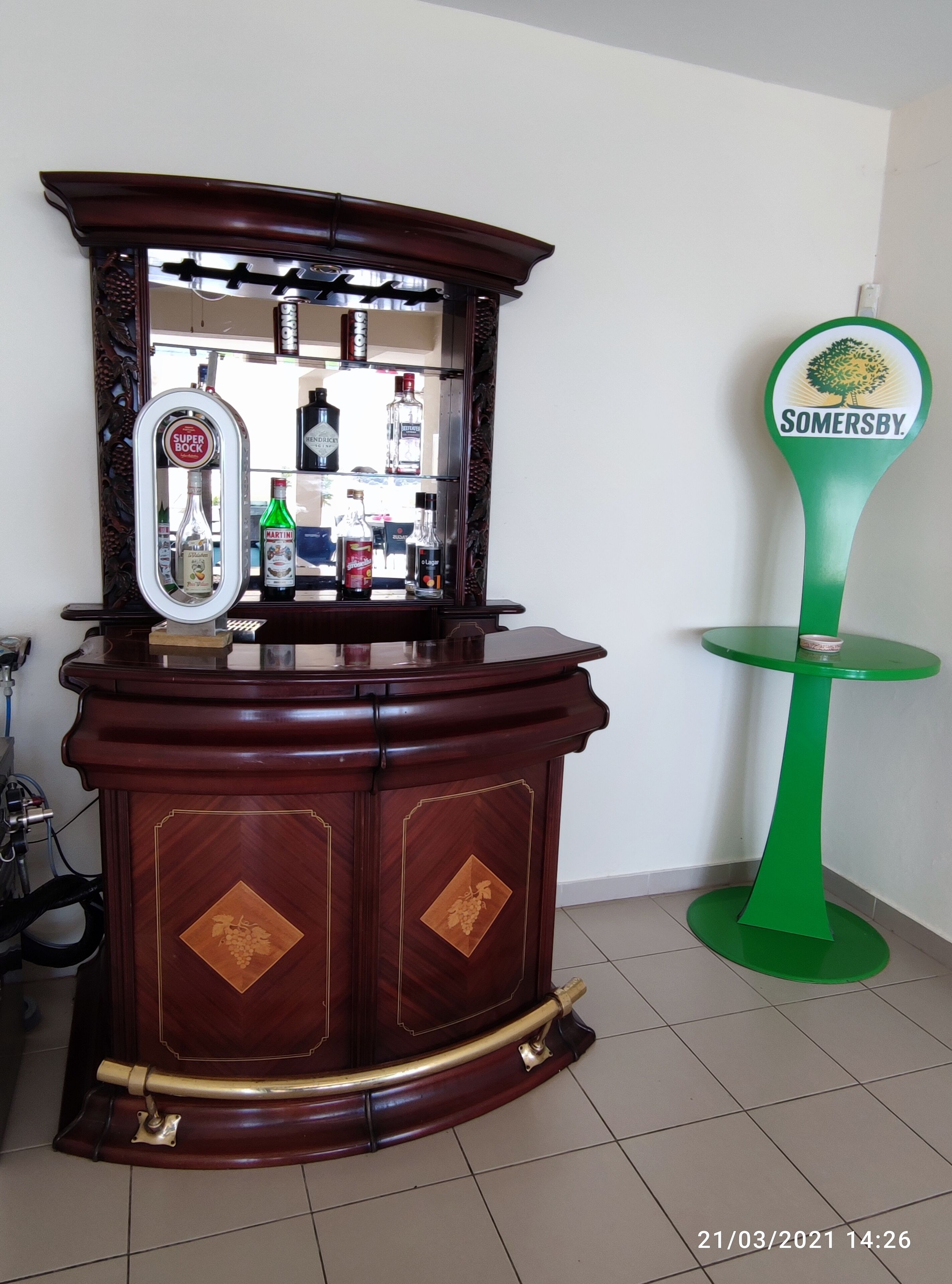 A bar area with a wooden cabinet and a green table with a 'Somersby' sign.