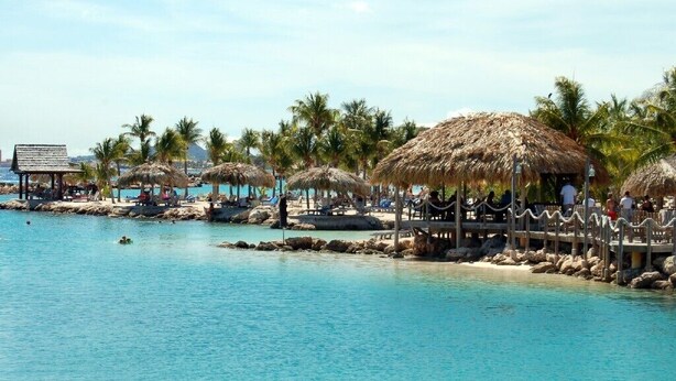A beach resort with thatched umbrellas, lounge chairs, and a clear blue pool. - CURACAO OCEAN FRONT APARTMENT WITH PRIVATE DOCK AND A FANTASTIC VIEW (Willemstad)