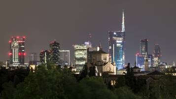 Nachtansicht einer Stadt mit beleuchteten Wolkenkratzern und einer markanten Kirche im Vordergrund.