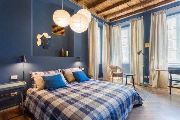 A bedroom with a checkered bedspread, a desk, and a chair.