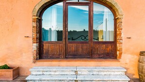 Un amplio ventanal arqueado con contraventanas de madera, base de piedra y barandilla metálica.