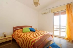 A bedroom with a bed, a nightstand, a window with curtains, and a ceiling fan.