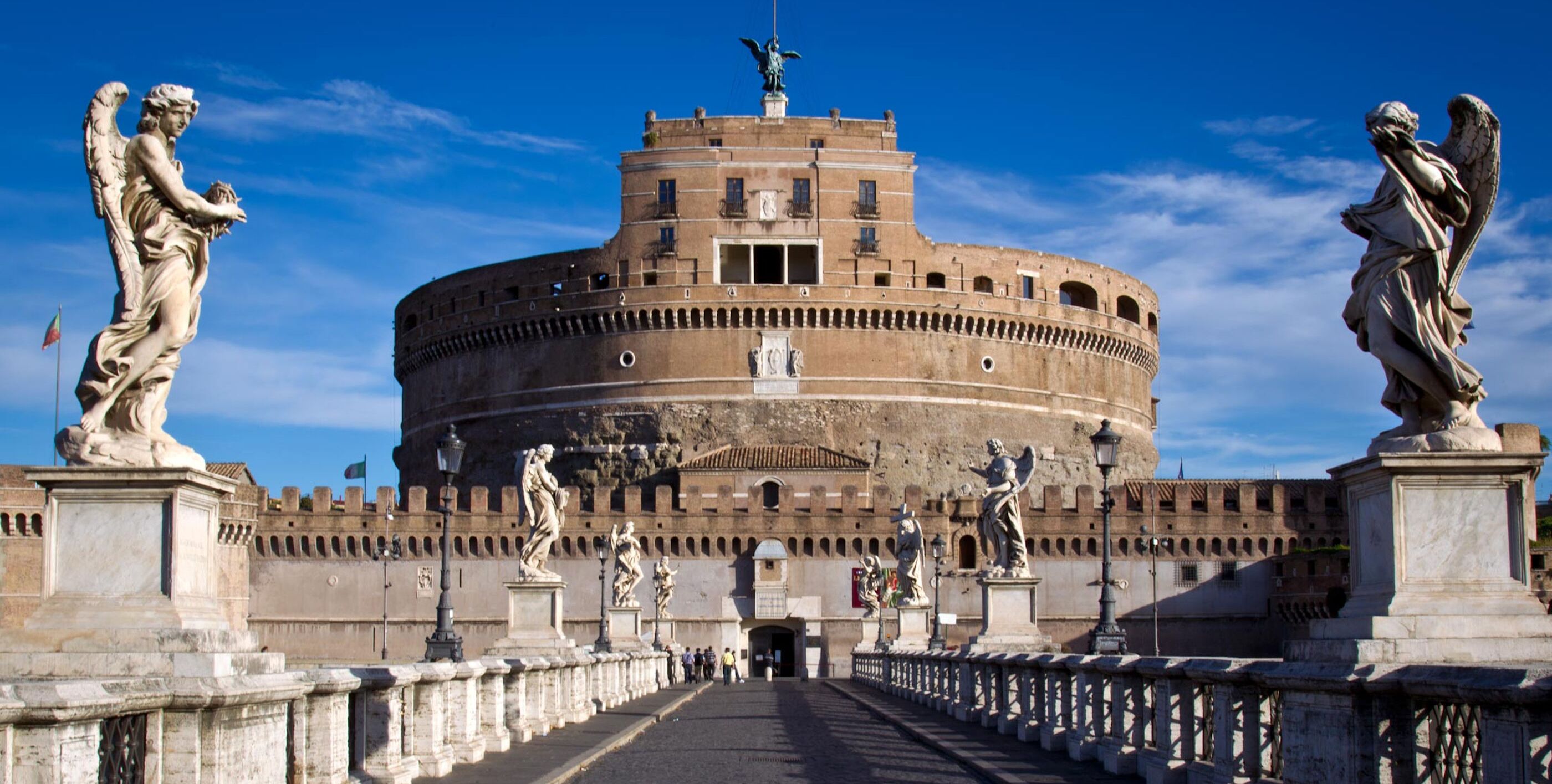 A historical building with a central circular structure, flanked by statues on either side.