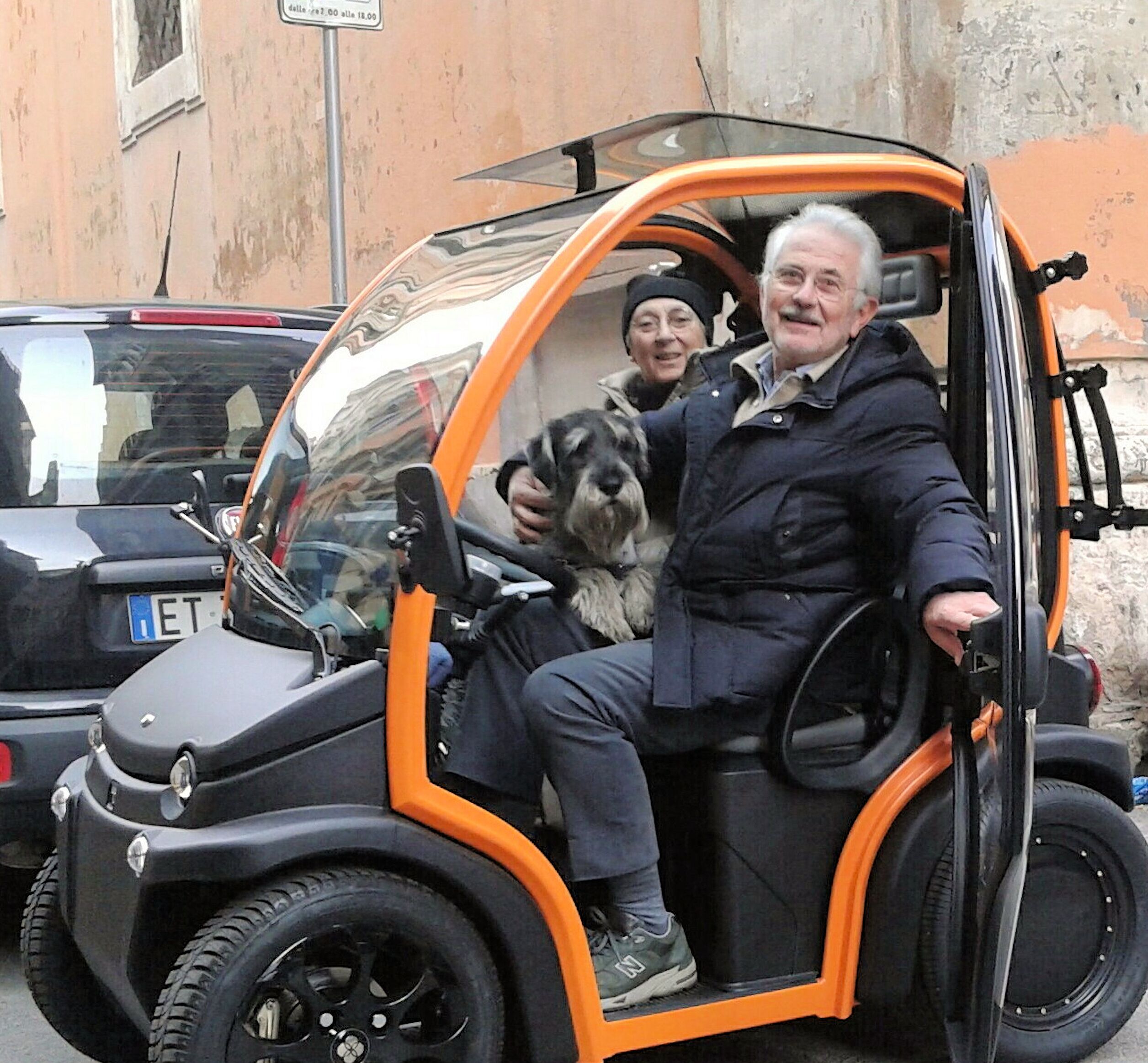 Un pequeño vehículo naranja con techo transparente, asiento negro y espejo retrovisor.