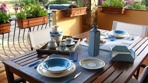 Mesa de jantar posta com pratos, tigelas e xícaras azuis e brancas, um vaso azul e uma bandeja de metal.