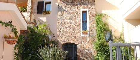Un bâtiment doté d’une façade en pierre, d’une porte noire et de plantes en pot.