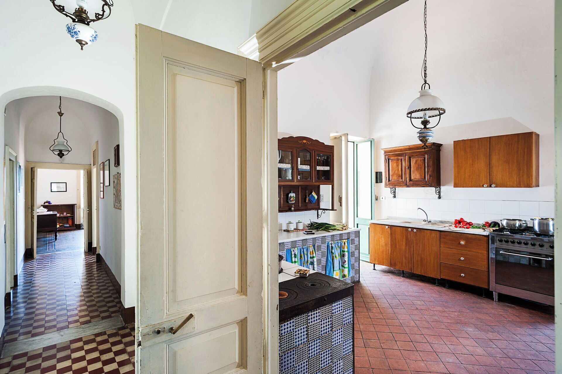 A kitchen with wooden cabinets, a stove, and a hanging light fixture.
