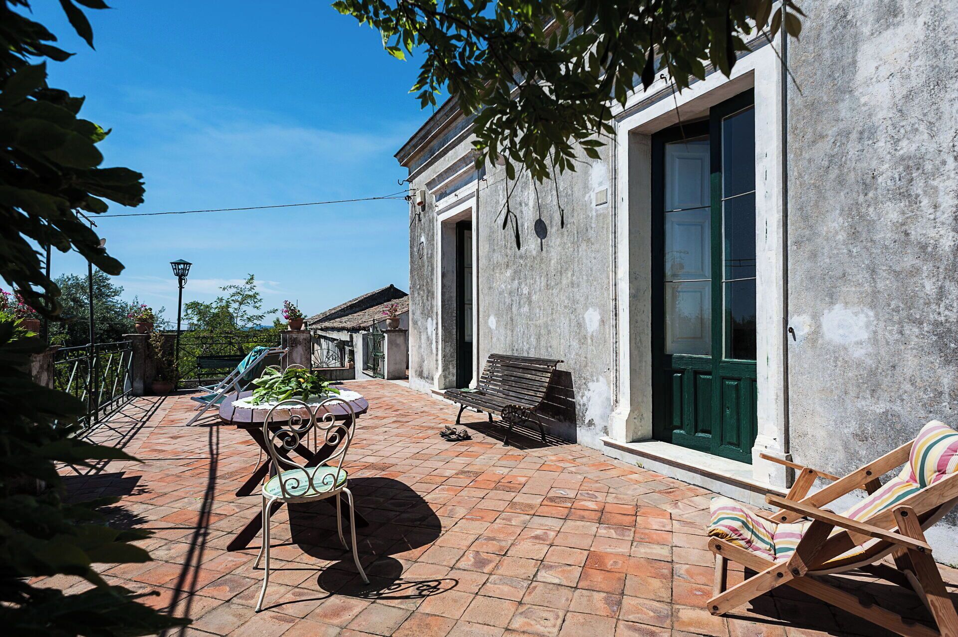 Un patio con una mesa, sillas y un banco.