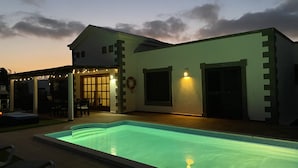 A modern house with a swimming pool, a covered patio, and a well-lit entrance. - Luxury villa - private pool with towels, super fast wifi, multiple language TV (Playa Blanca)