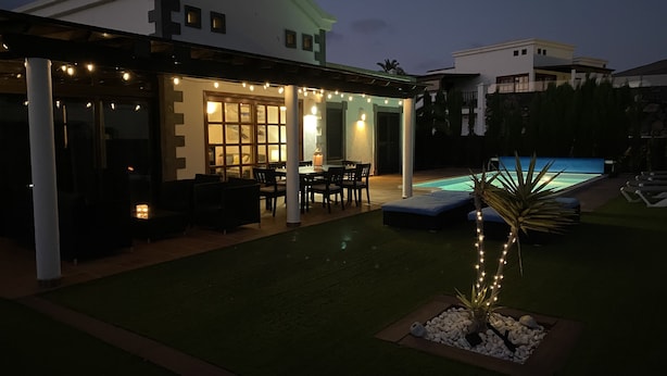 A covered outdoor patio with a pool, seating area, and string lights. - Luxury villa - private pool with towels, super fast wifi, multiple language TV (Playa Blanca)