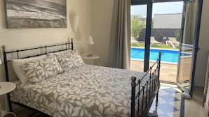 A bedroom with a bed, a nightstand, a lamp, and a view of an outdoor swimming pool. - Luxury villa - private pool with towels, super fast wifi, multiple language TV (Playa Blanca)