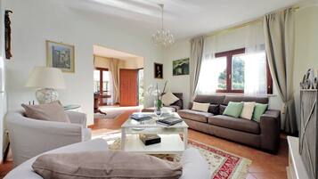 A living room with a sofa, a coffee table, and a couch. There is a door leading to another room.