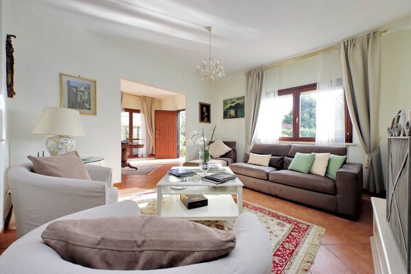 Un salon avec un canapé, une table basse et un divan. Une porte donne accès à une autre pièce.