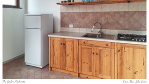 Eine Küche mit Holzausstattung, einem weißen Kühlschrank, einer gefliesten Spritzschutzwand und einem Gasherd.