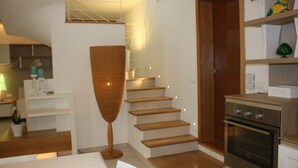 Une cuisine moderne avec un plancher en bois, un four encastré et un escalier menant à un niveau supérieur.
