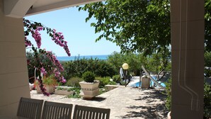 Un espace patio avec vue sur la mer, des sièges d’extérieur et des plantes en pot.