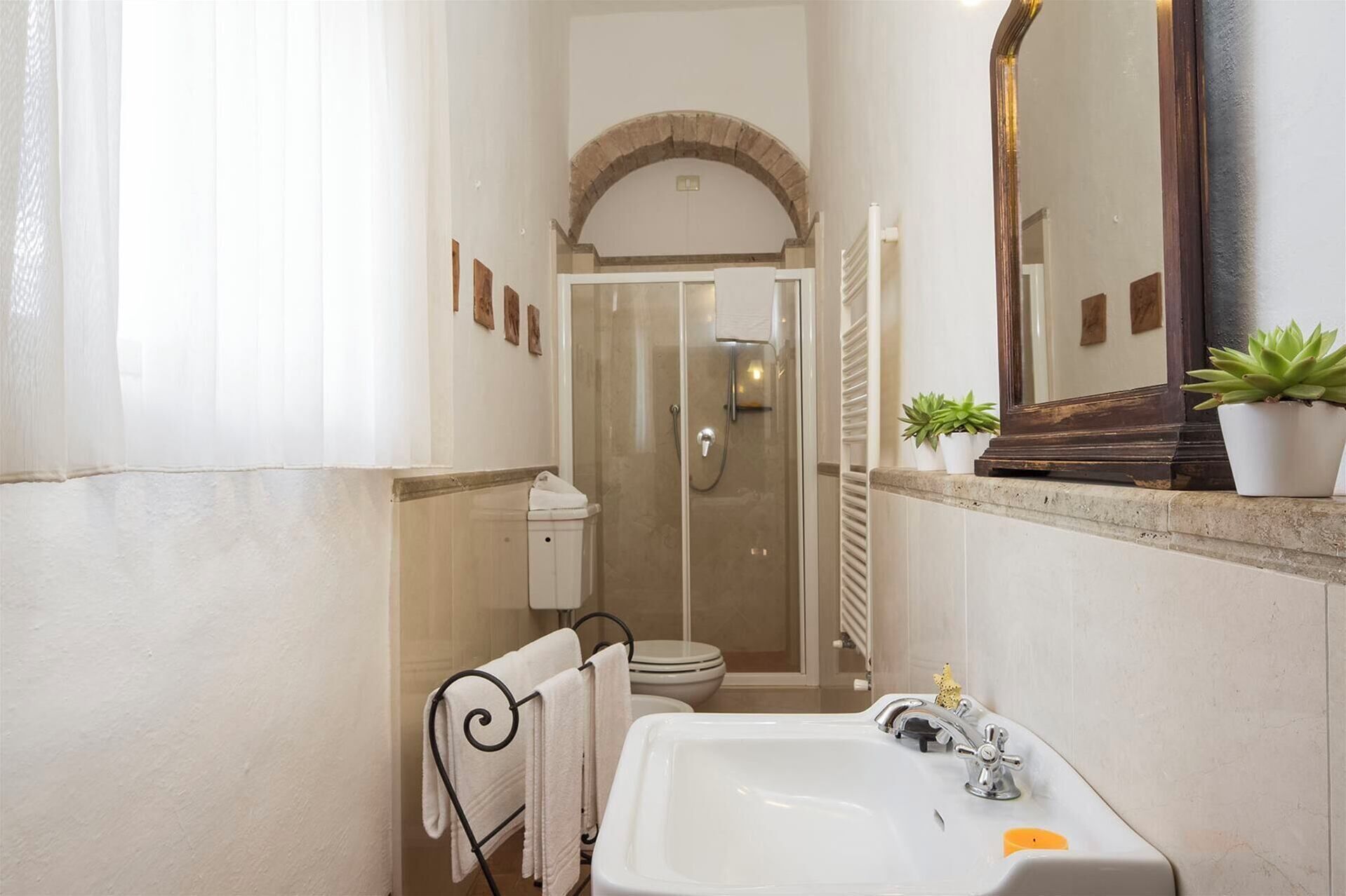 A narrow bathroom with a shower, toilet, and sink.