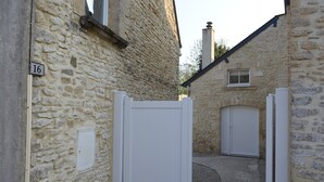 A stone building with a white door and a small window. A number '16' is visible on the wall. - Charming house, enclosed garden, 3 min from Arromanches and the beaches (Ryes)