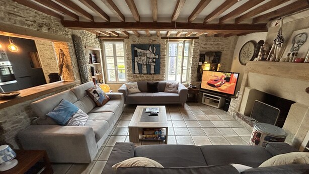 A cozy living room with a fireplace, stone walls, and a television. - Charming house, enclosed garden, 3 min from Arromanches and the beaches (Ryes)