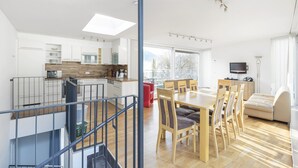 Een modern appartement met keuken, eetruimte en woonkamer. Het heeft een trap, een balkon en grote ramen.