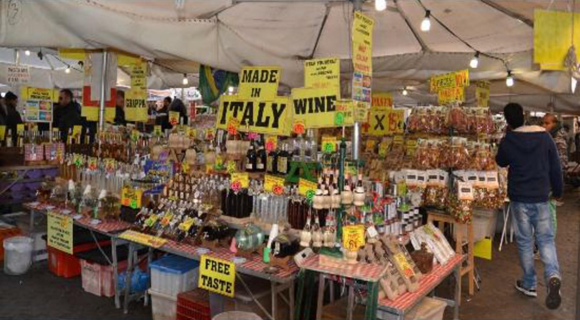 A market stall with various food items and a sign indicating free taste samples.