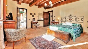 A bedroom with a wooden ceiling, a bed with a green floral bedspread, a wooden chest of drawers, a chair, a desk, and a mirror. - It's pure magic! Dont' miss this unique chance...a beautiful view and an exclusive stay will take yo (Serrapetrona)