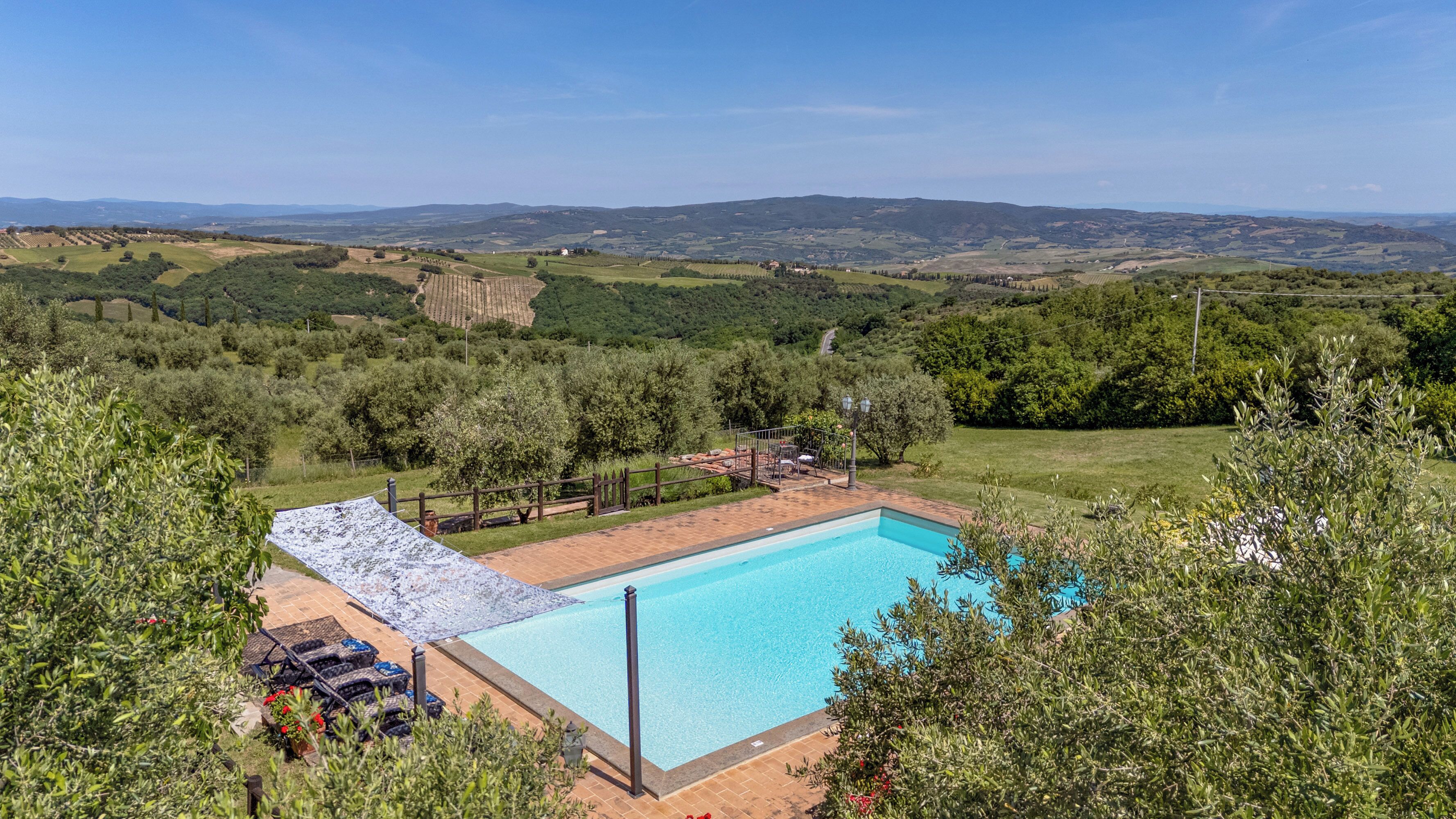 Une piscine offrant une vue sur des collines verdoyantes et des vignobles en arrière-plan.