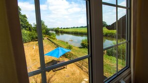 A view through a window of a river, grassy area, and a blue umbrella. - Historic detached cottage, on the banks of the River Severn Nr Upton & Malvern (Worcestershire)