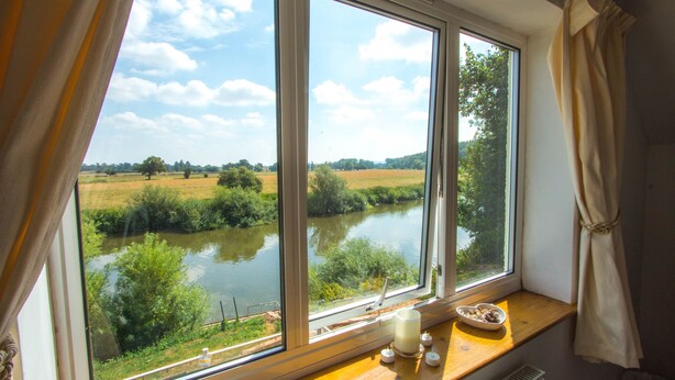 A room with a large window overlooking a river and fields. - Historic detached cottage, on the banks of the River Severn Nr Upton & Malvern (Worcestershire)