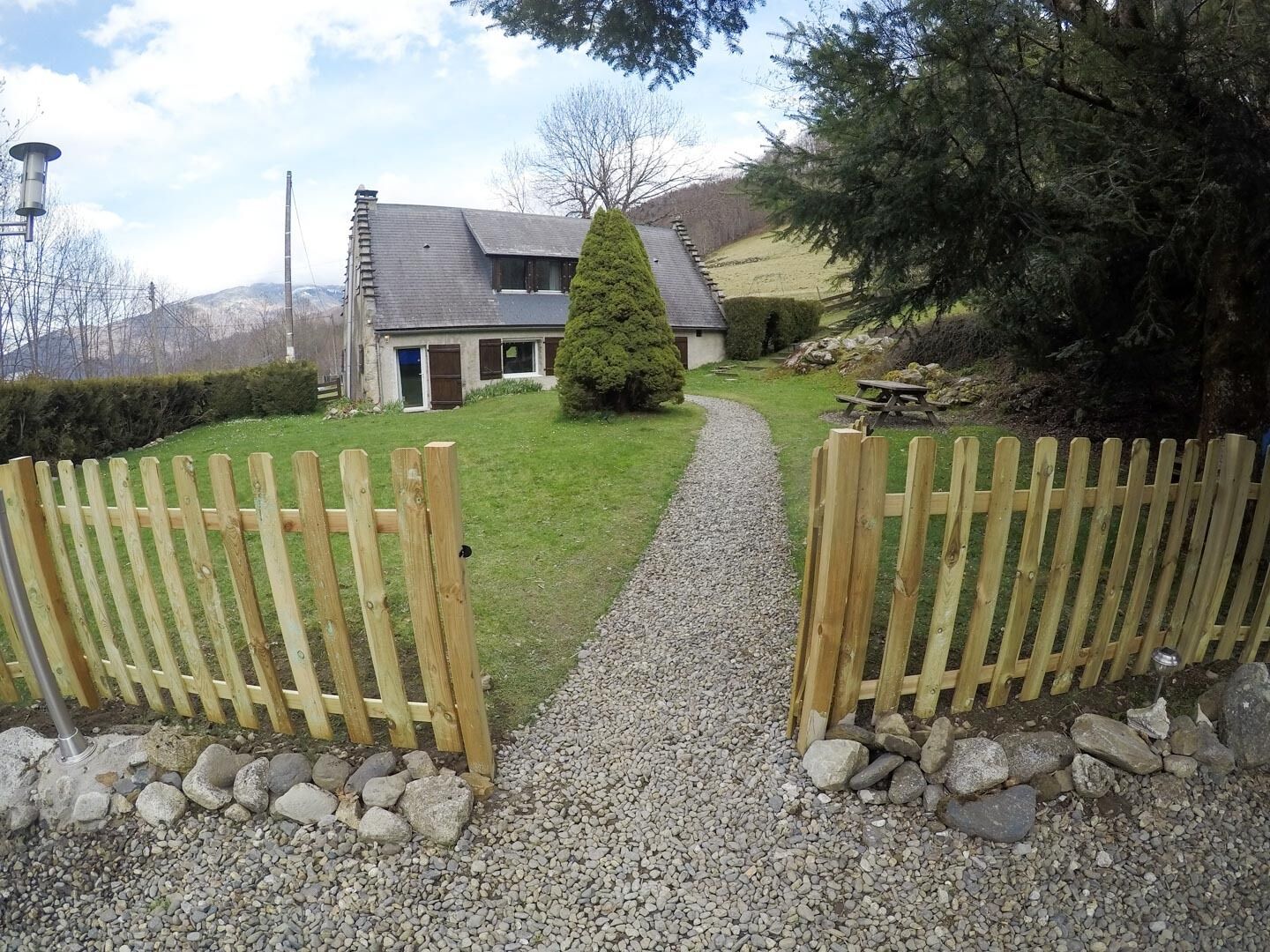 A gravel pathway leading to a house with a wooden fence on either side.