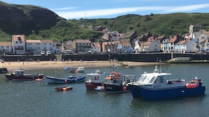 A harbor with boats docked, a sandy beach, and buildings along the shore.