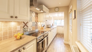 A kitchen with white cabinets, a stove, and a bowl of fruit on the counter.