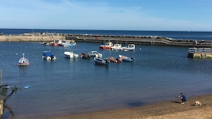 A harbor with various boats docked, a sandy beach, and a stone pier.