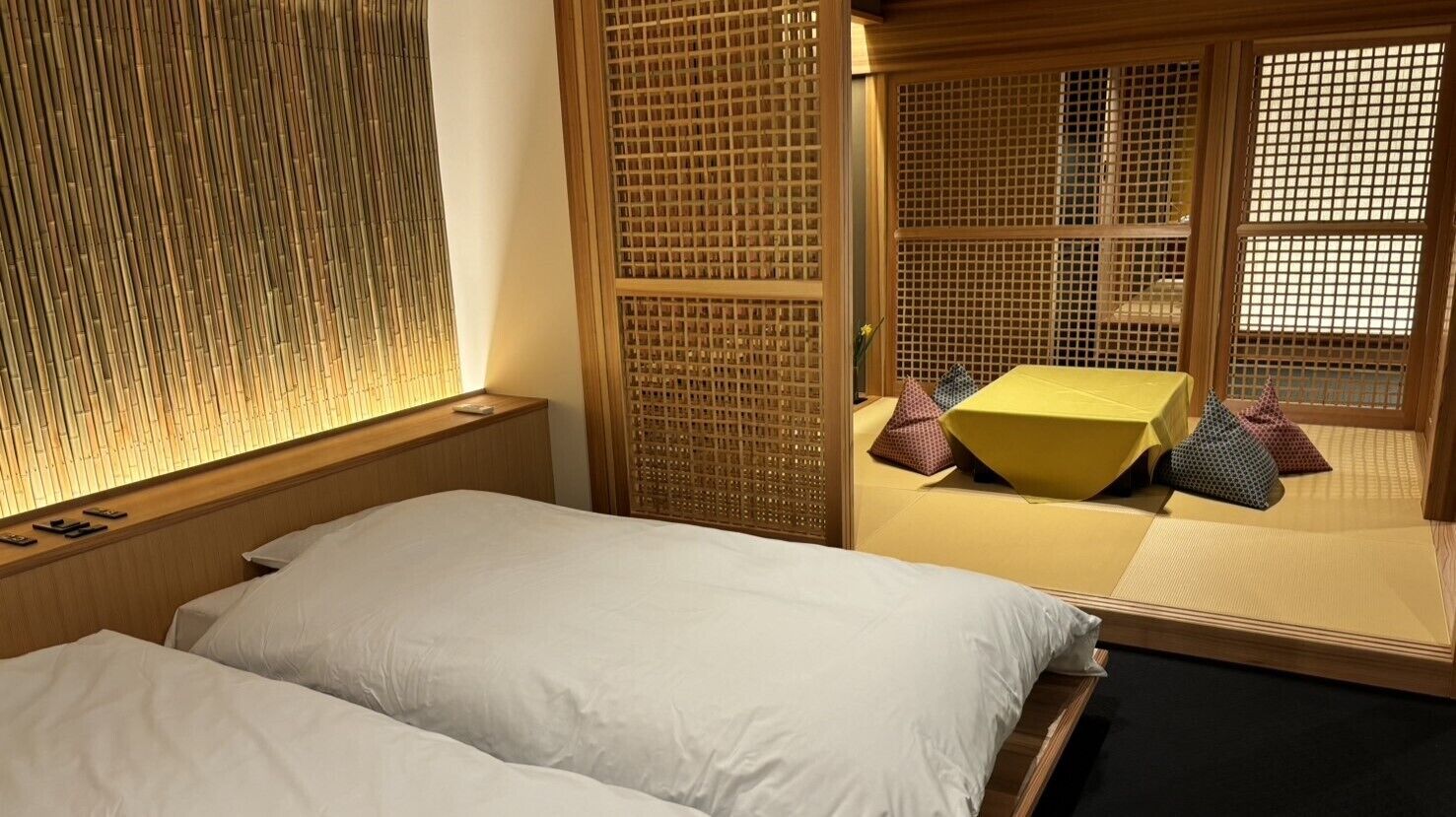 A traditional Japanese-style room with tatami flooring, a low wooden bed, and a sliding door with a lattice design.