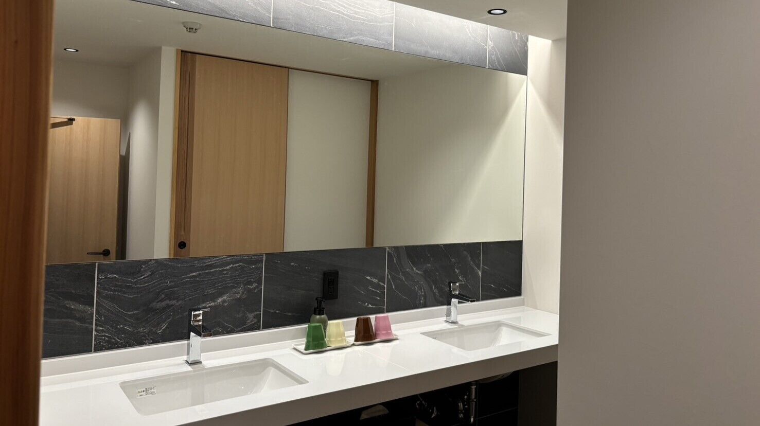 A bathroom with two sinks, a mirror, and a wooden door.