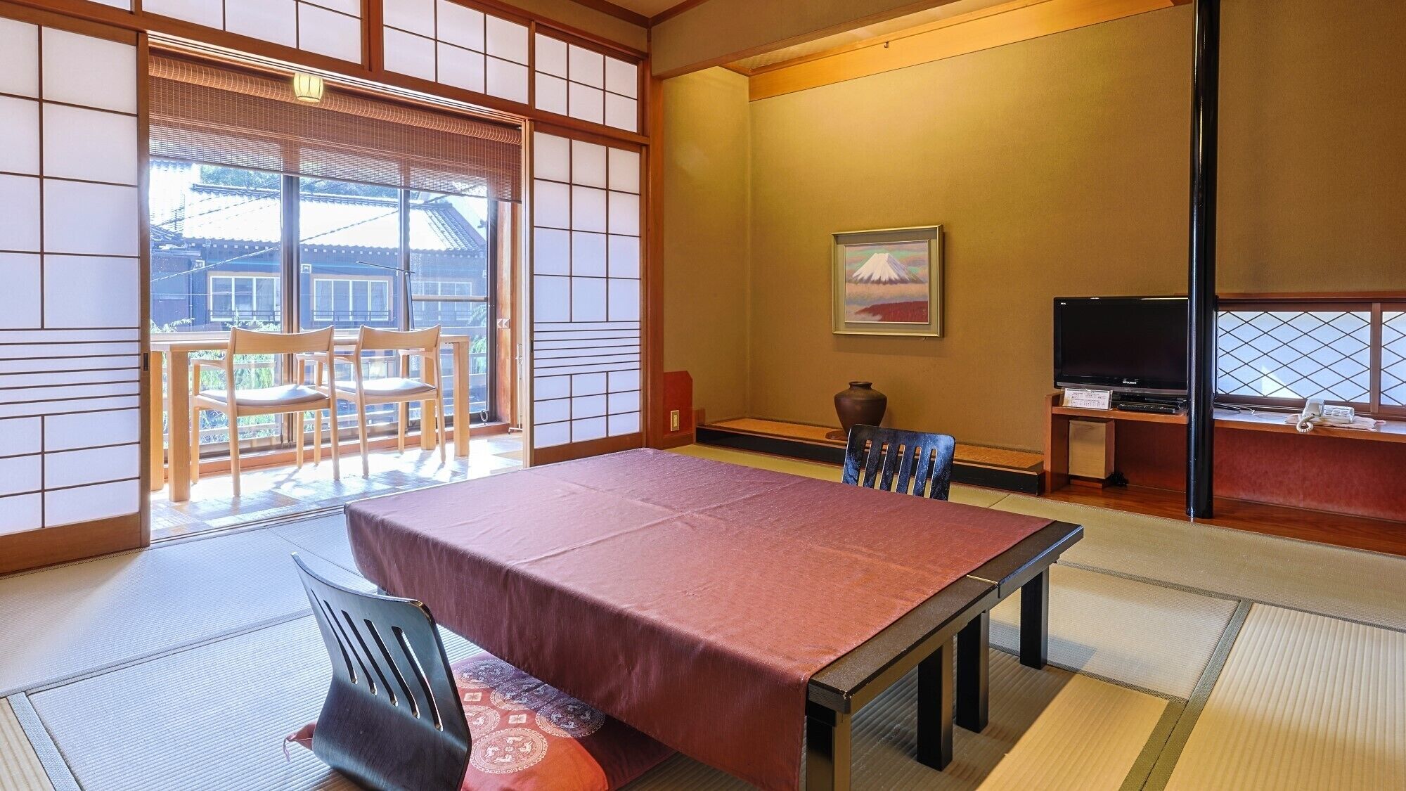 A traditional Japanese room with tatami flooring, a low table, and a television.