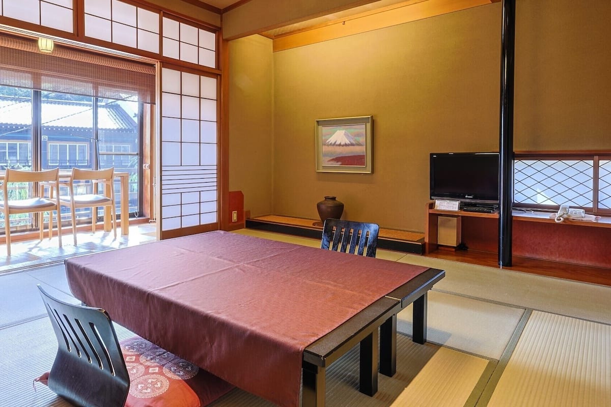 A traditional Japanese room with tatami flooring, a low table, and a television.