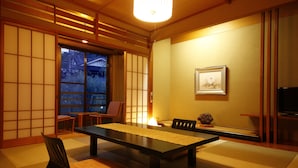Una habitación tradicional japonesa con suelo de tatami, una mesa baja y puertas correderas.