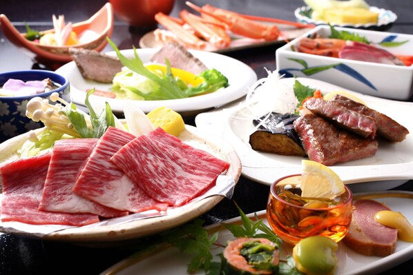A variety of dishes including sashimi, vegetables, and meat, arranged on multiple plates. - Kinosaki Yamamotoya (Toyooka)