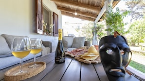 Une table en bois avec une bouteille de vin, deux verres, un masque et une assiette de nourriture.