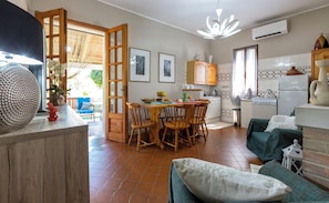 Een gezellige woonkamer met een eethoek, een keuken en een groot raam.