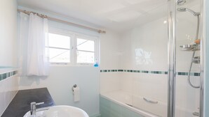 A bathroom with a bathtub, shower, and sink.