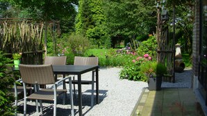 Une terrasse extérieure avec des meubles en osier et un chemin de gravier.