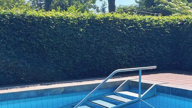 Une piscine avec un escalier en métal et des marches carrelées.