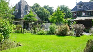 Une grande maison avec un jardin, un belvédère et un étang.