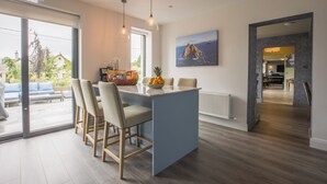 Una cocina moderna con una isla central, taburetes de bar y vistas al exterior.