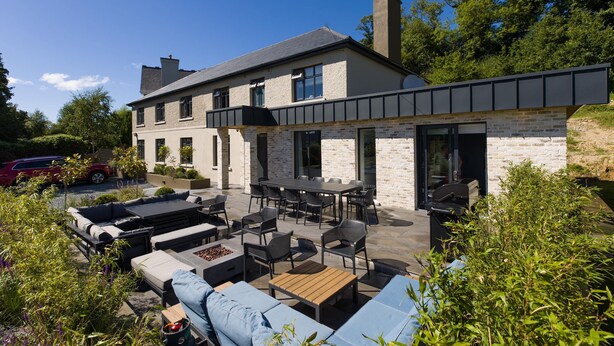 Una casa moderna con un patio amueblado al aire libre y una barbacoa.