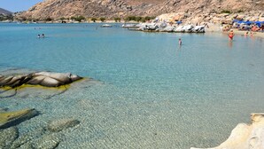 A clear blue sea with rocky formations and people swimming.
