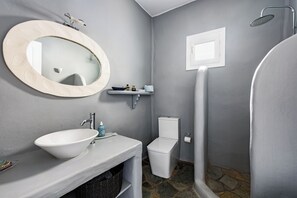 A bathroom with a white sink, a round mirror, a toilet, and a shower. - VILLA GALAZIO, PRIVATE POOL, SEA VIEWS AND SUNSETS OVER ANTIPAROS (Paros)
